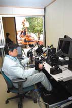 遥控机器人通过驾驶考试＂></td>
             </tr>
            </tbody>
           </table>
           <p>2002年12月，川崎东电建设有限公司和日本最大的公共研究机构国家先进工业科学技术研究所(AIST)完成了世界上第一次成功的演示，演示了一种远程控制的人形机器人在室外和全天候运行商业工业车辆。</p>
           <p>HRP-1S机器人坐在挖掘机操作员的座位上，在执行挖掘任务时“驾驶”车辆。穿上雨和灰尘的特殊防护装备，HRP-1S证明了即使在恶劣天气下也能执行任务。</p>
           <p>该测试是由日本经济产业省实施的人形机器人项目(HRP)的一个组成部分。川崎重工负责开发遥控方法和系统，以及其他控制机器人动作的核心技术。</p>
           <p>为了使工业车辆能够在危险和恶劣的环境中执行任务，已经进行了许多尝试。通过用遥控方式控制的机器人操作员取代人类，这一发展将使在建筑工地或遭受自然灾害的危险地区更快速、更安全地工作。</p>
           <p>目前，研发团队正在开发可以独立登上工业车辆的无线遥控装置和机器人。通过模拟实际工作条件进行实验，评估机器人的工作性能/生产率，川崎将设计出仿人机器人的远程控制技术。</p>
          </div>
          <!--フリーHTML-->
          <!-- /section-->
         </div>
         <!-- /contents -->
        </div>
        <!-- / #mainContentsArea -->
       </div>
       <nav id=
